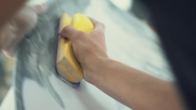 house painter manually polishes the surface of the car