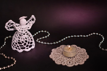 Christmas decoration on black background. White angel, candle, silver beads