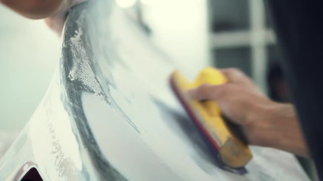 house painter manually polishes the surface of the car