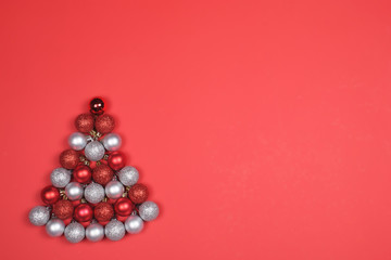 Baubles forming Christmas tree on red background