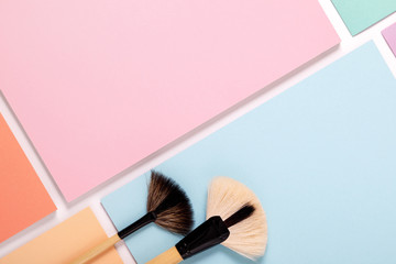 makeup brushes on pastel paper pink background