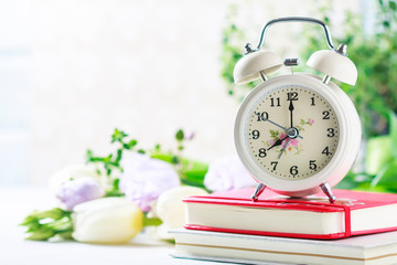 Retro alarm clock, notebook and spring flowers.