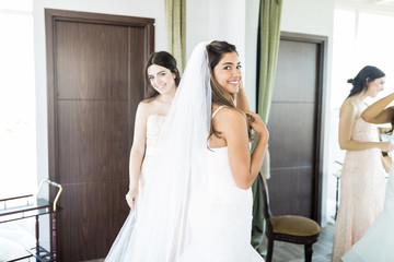 Young Woman Getting Dressed For Wedding Ceremony