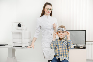 Pediatric Doctor ophthalmologist checks vision of child boy. Concept selection of glasses lenses.