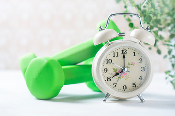 Alarm clock and dumbbells, concept of diet.