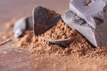 dark chocolate, cocoa solids and cocoa powder over wooden background