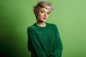 Fashion portrait of young woman with blond short hair isoalted on green background