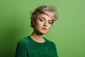 Fashion portrait of young woman with blond short hair isoalted on green background