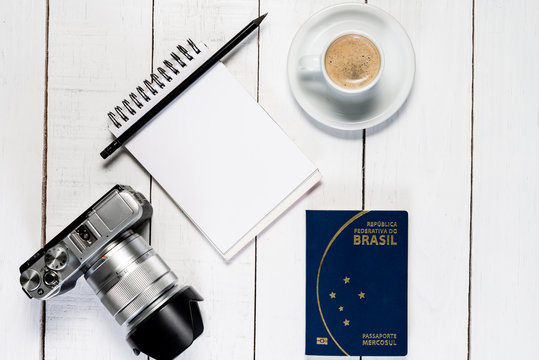Camera on white wooden background. Notepad with white space and coffee. Brazilian passaport.