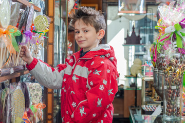 boy chooses lollipop in the candy store