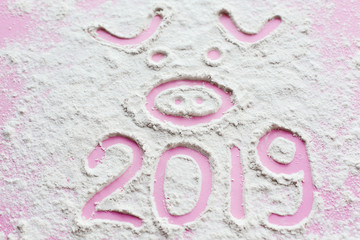 Pig and 2019 year. Cute pig face drawn on flour or snow and 2019 on pink background. Happy new year. Chinese new year symbol. Creative pink piggy photo