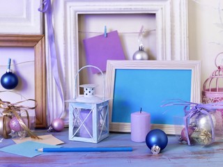 Seasonal festive interior composition of candles, Christmas decor, wooden vintage frames, decorative lamps, paper for notes on a wooden table, the concept of congratulations on the holiday, home comfo