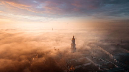 Aerial view of Kiev Pechersk Lavra at dawn and the city covered with thick fog in the background.