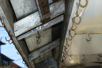 Background surface of old and rusty hooks hanging on the roof of shop