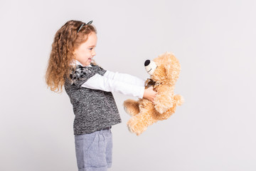 A little girl with a bear standing on a white background