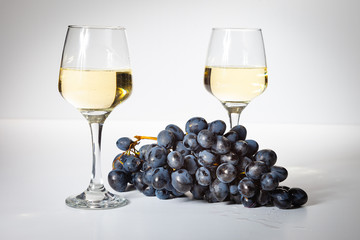 A glass of white wine. Bunch of grapes on a white background.
