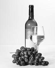Fototapeta premium A glass of white wine, a bunch of grapes, an open bottle.