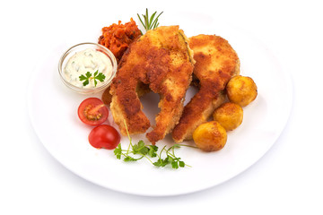 Crispy breaded fish fillet with herbs, sauce and potatoes, isolated on a white background. Close-up