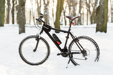 Winter season cycling. Black bicycle on the snow. Sport at any time of year concept.