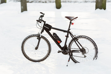 Winter season cycling. Black bicycle on the snow. Sport at any time of year concept.