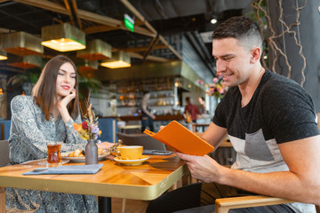 electronic menu or bill in the restaurant. Pretty woman and Sports man drinking coffee and relaxing in cafe oriental style. Breakfast, pleasant morning, the beginning of the working day