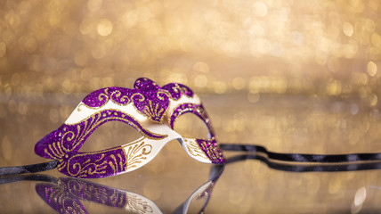 Carnival mask on golden bokeh background, copy space