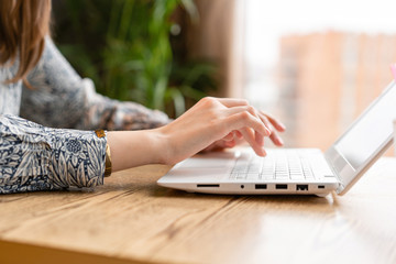 Young woman Typing on the keyboard, chatting, maintains a blog. Freelancer work in modern coworking. Successful people, businessman in comfortable cafe . Reading text during work on netbook.
