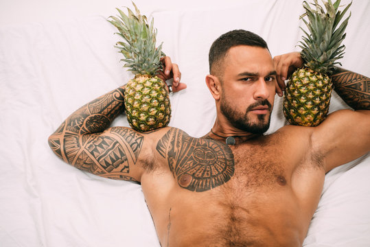 Miami man with pineapple. Tropical party. Miami summer party. Latino american brutal man relaxing on beach. Portrait of handsome fashion man model on white background for your party advertising.