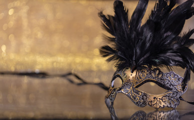 Carnival mask with feathers on golden bokeh background