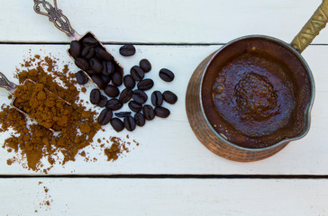 Coffee pot and coffee beans on wooden white background.