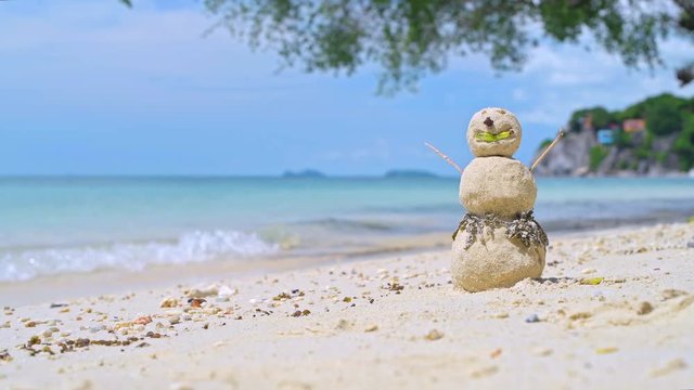 New year on the coast of Southeast Asia. Snowman from sand on the beach in the surf on a sunny day