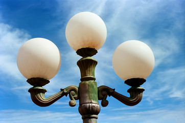 Vintage street lamps against a blue cloudy sky