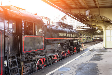 Retro steam locomotive train stands on the railway station.