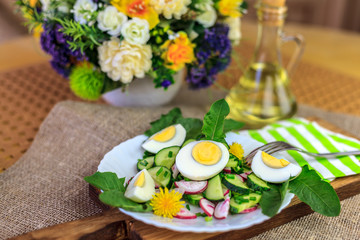 Salad of dandelions, Healthy spring salad of young leaves of dandelion, cucumber, radish and egg on a plate closeup