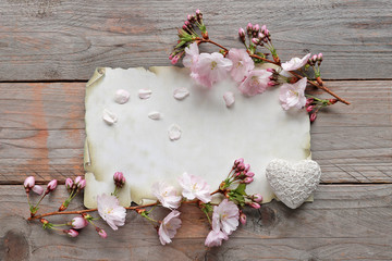 Sakura flowers with petals and paper  on wooden background 
