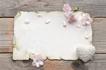 Sakura flowers  with paper and heart on wooden background 