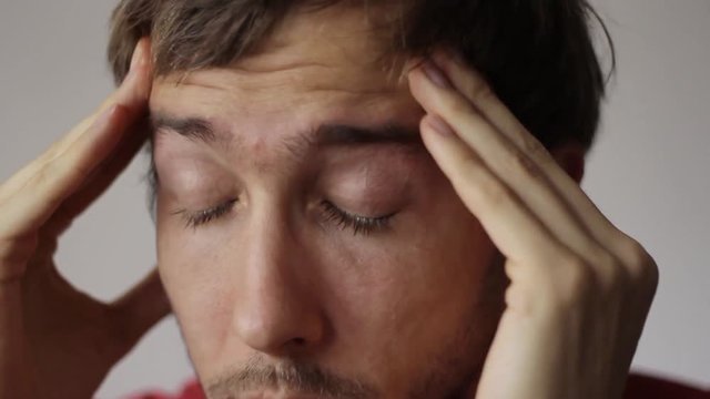Close-up of a man showing gestures of painful headache.
