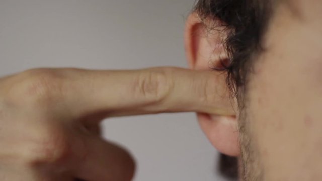 Close-up portrait of a young man plug his ear.