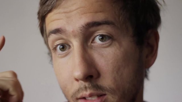 Close-up portrait of a young man showing gestures: Thinking.
