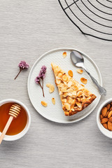 Sliced apple and almond pie on plate over the grey tablecloth. Top view with copy space for text.