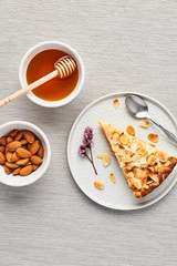 Sliced apple and almond pie on plate over the grey tablecloth. Top view with copy space for text.