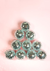 disco balls for decoration party on pastel pink gradient background. Light silver disco balls making a shape of fir tree. Christmas New year concept. top view, flat lay. Frame with room for copy.