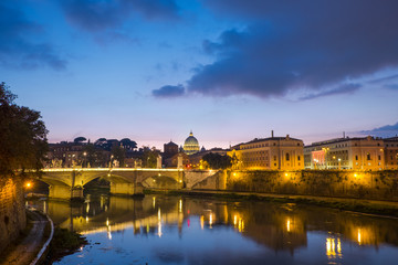View of Rome at dusk, Vittorio Emanuele bridge, cupola of Saint Peter's Dome and Vatican, with waters of Tiber river in the front