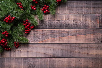 Christmas background concept. Top view of Christmas spruce branches, red berries and bell on old wooden background.