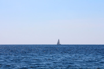 small sailing boat alone on the horizon line