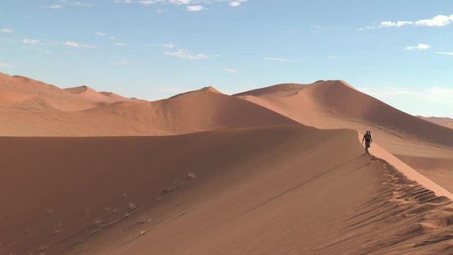 People walk along the ridge of the dune.