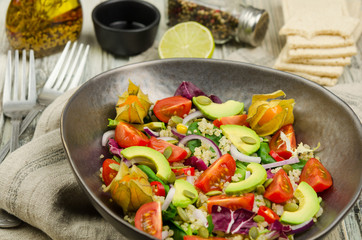 Fresh healthy summer salad with quinoa, avocado and cherry tomatoes. Fresh healthy quinoa salad on wooden background close up. Food and health. Superfood. 