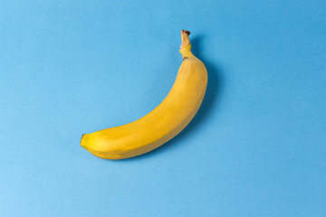 Minimalism style. Fruit pattern with yellow banana over blue background.