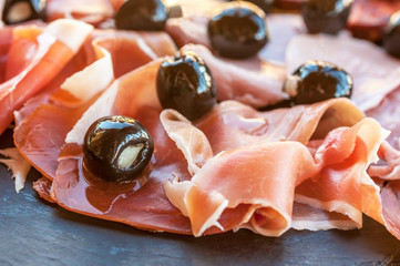 Slices of Spanish Jamon Iberico and olives