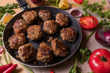 Homemade rabeef meatballs on a pan, before cooking, with vegetables.